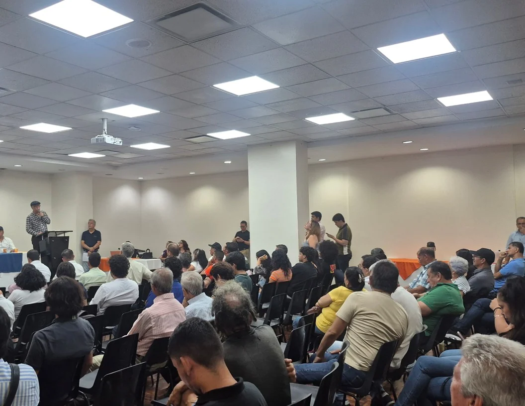 Numerosos asistentes posan frente al aviso de Dignidad & Compromiso durante reunión en Santander